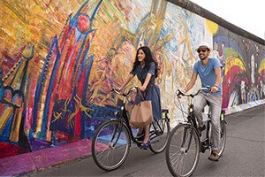 Una pareja pasea en bici por el Muro de Berlín. Autor: Turismo de Alemania.